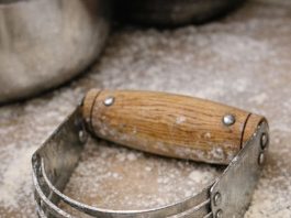 Spotted this U-shaped tool with multiple metal blades in my grandmother’s baking bin. It has a wooden handle but looks like some kind of strange knuckles.