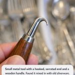 Small metal tool with a hooked, serrated end and a wooden handle. Found it mixed in with old silverware. Too sharp to be a spoon, too curved for a knife.